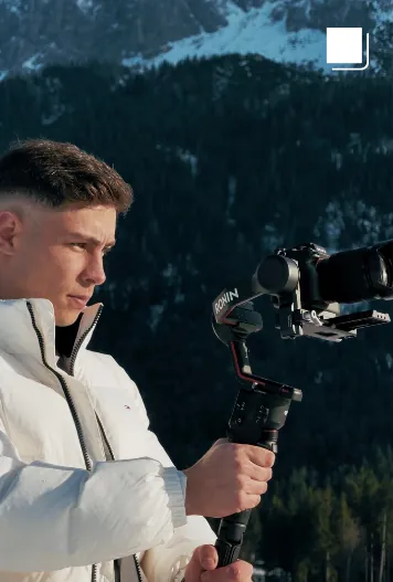 Videograf mit Gimbal vor Bergkulisse